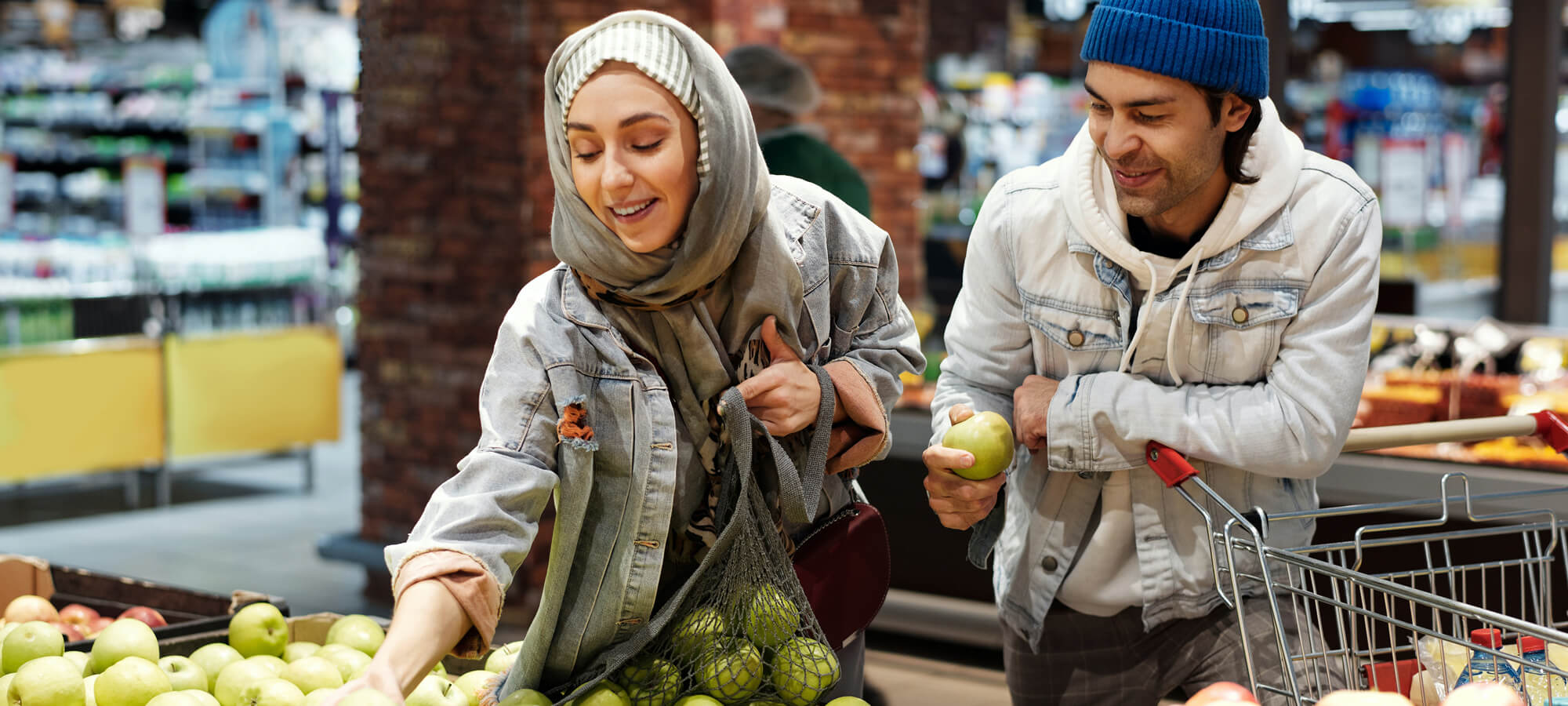 Kvinna och man som väljer frukt i i fruktdisken i en butik