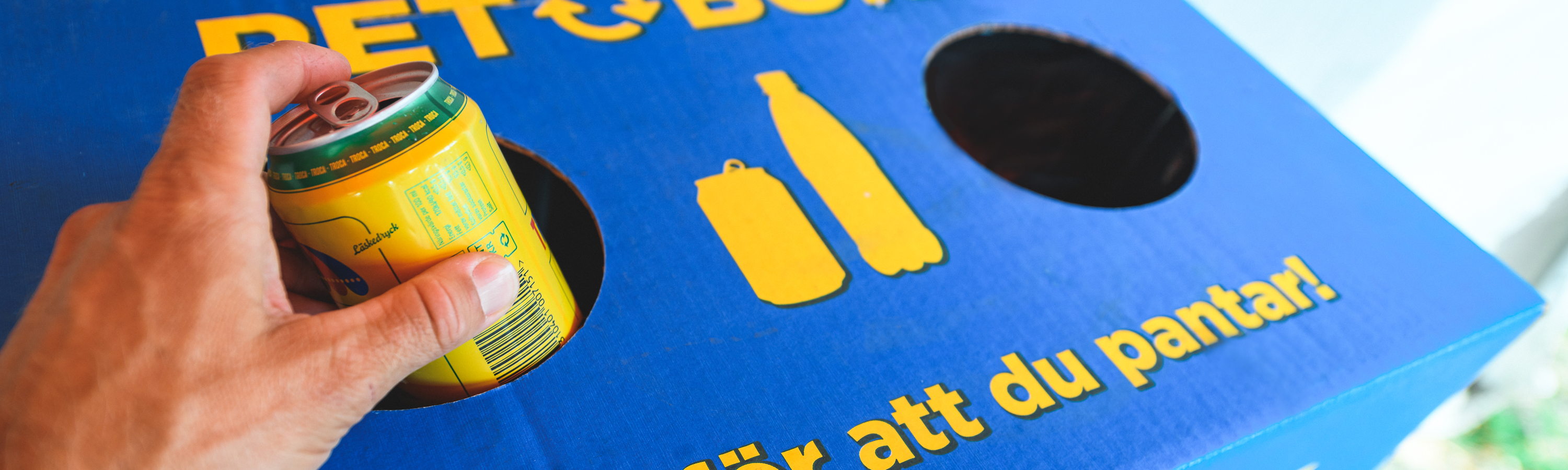 Hand som lämnar en pantburk i ett pantkärl